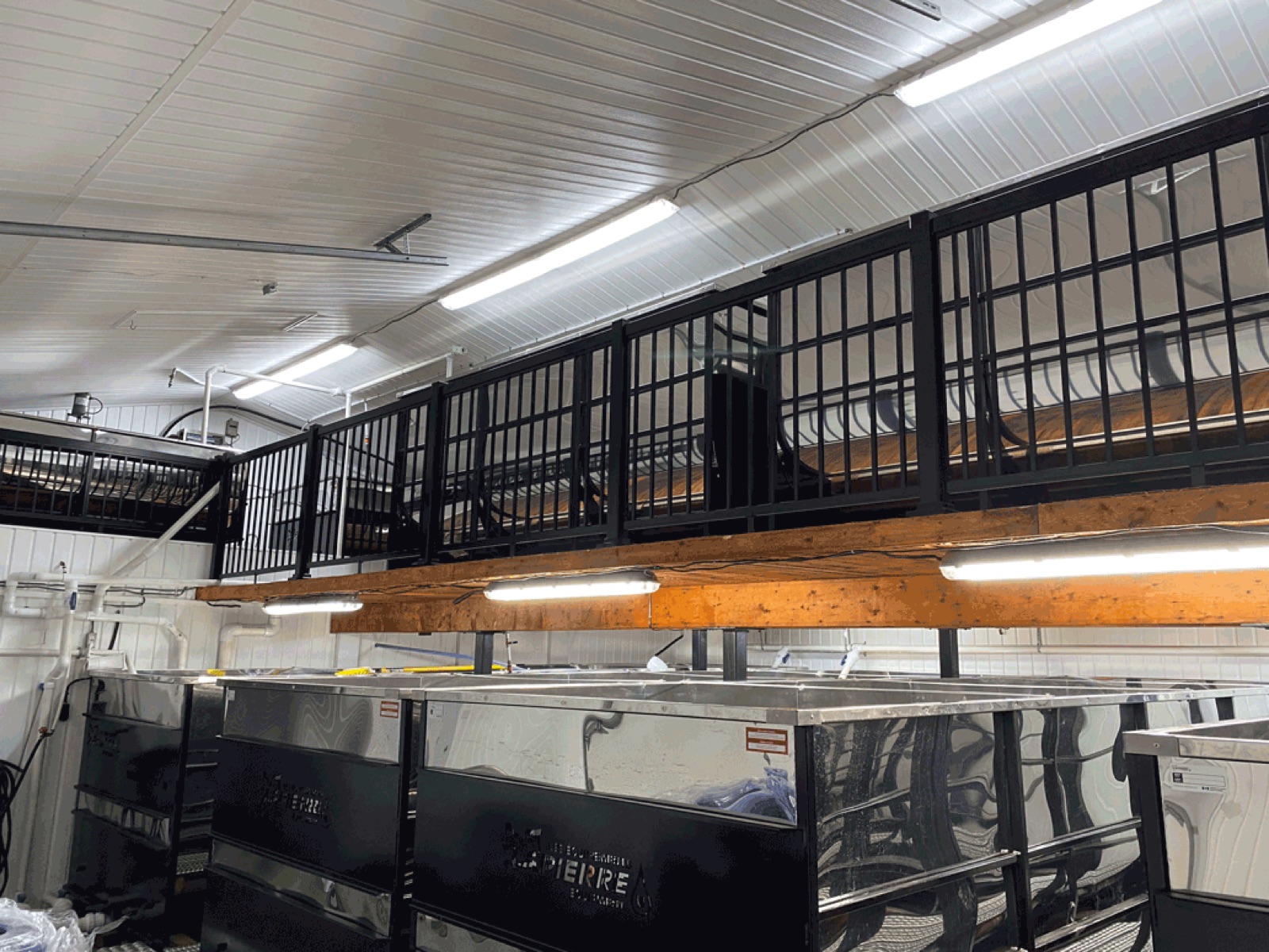 Intérieur de l'érablière : bassins en acier inoxydable sous une mezzanine de bois