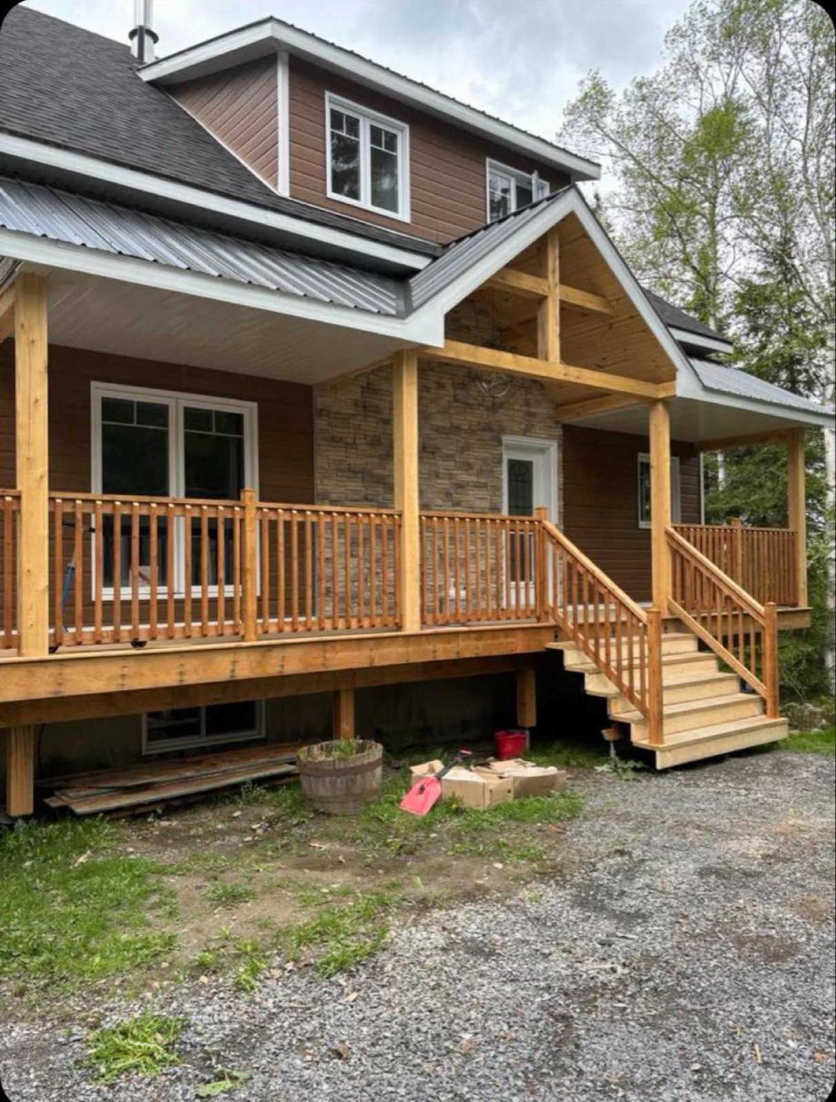 Galerie couverte en bois avec colonnes massives et pierre, ajoutée à une maison de campagne