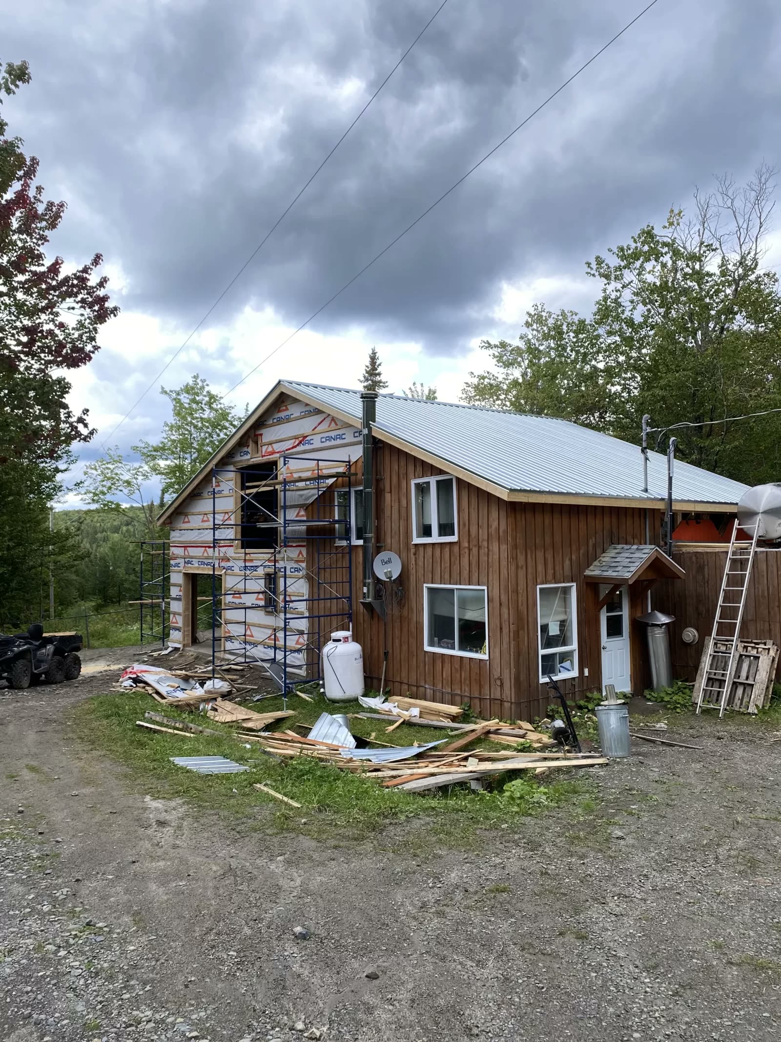 Chalet en bois en cours de construction avec échafaudage en milieu boisé