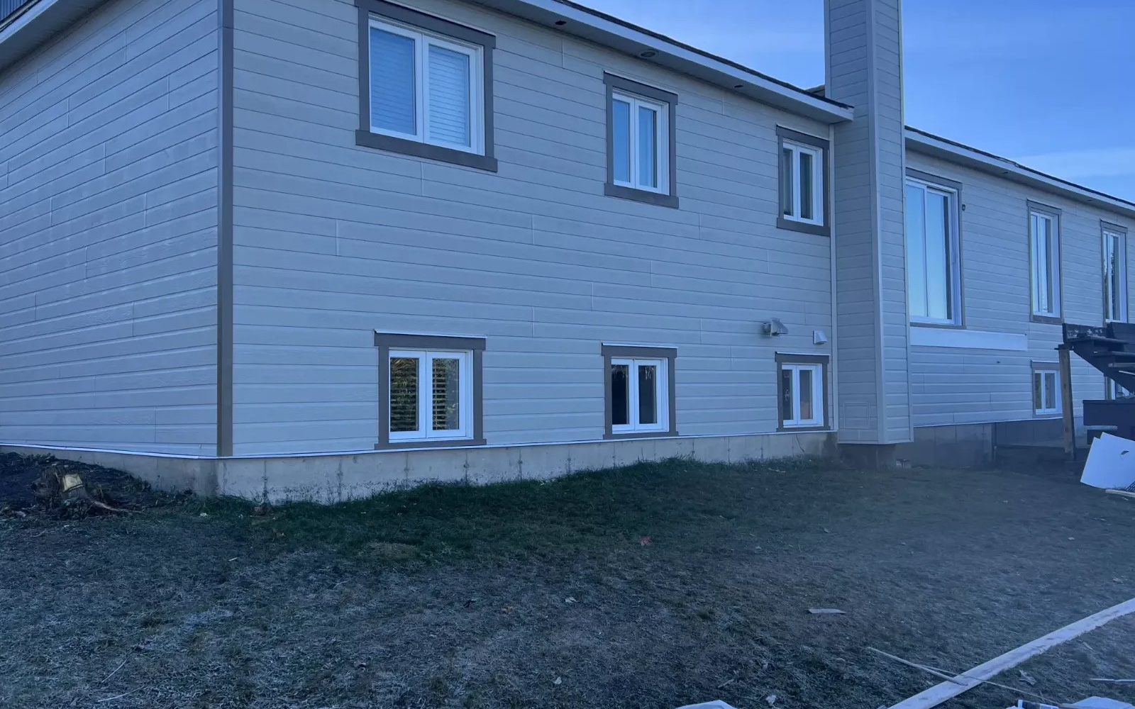 Même maison terminée : bardage beige, cheminée finie et finitions complètes